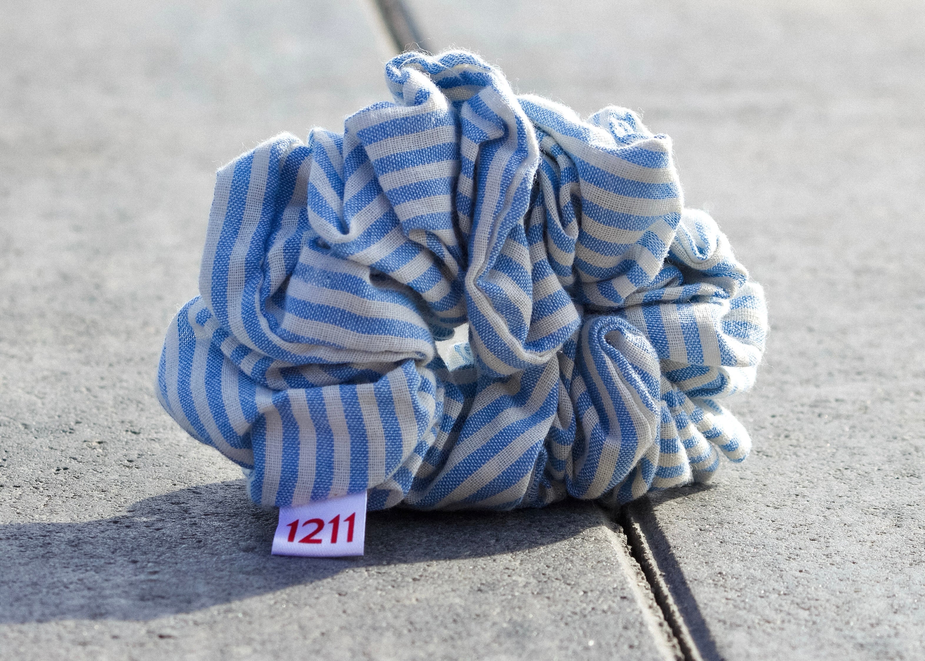 Blue scrunchie with white stripes, elegant hair accessory from Twelveeleven, perfect for everyday styling.