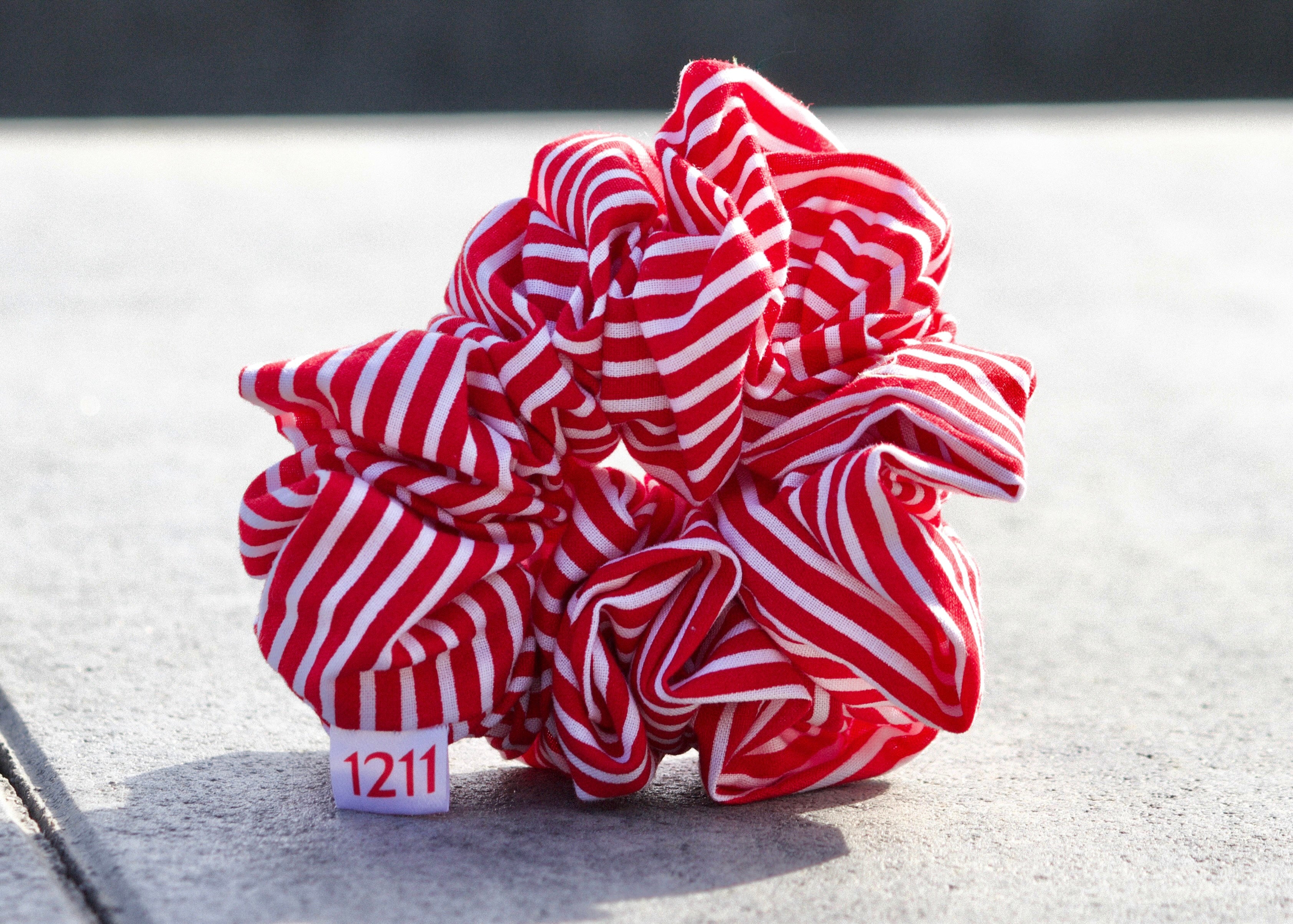 Red scrunchie with white stripes, elegant hair accessory from Twelveeleven, perfect for everyday styling.